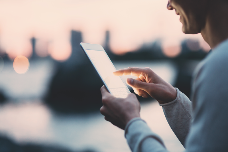 Young man texting on a tablet